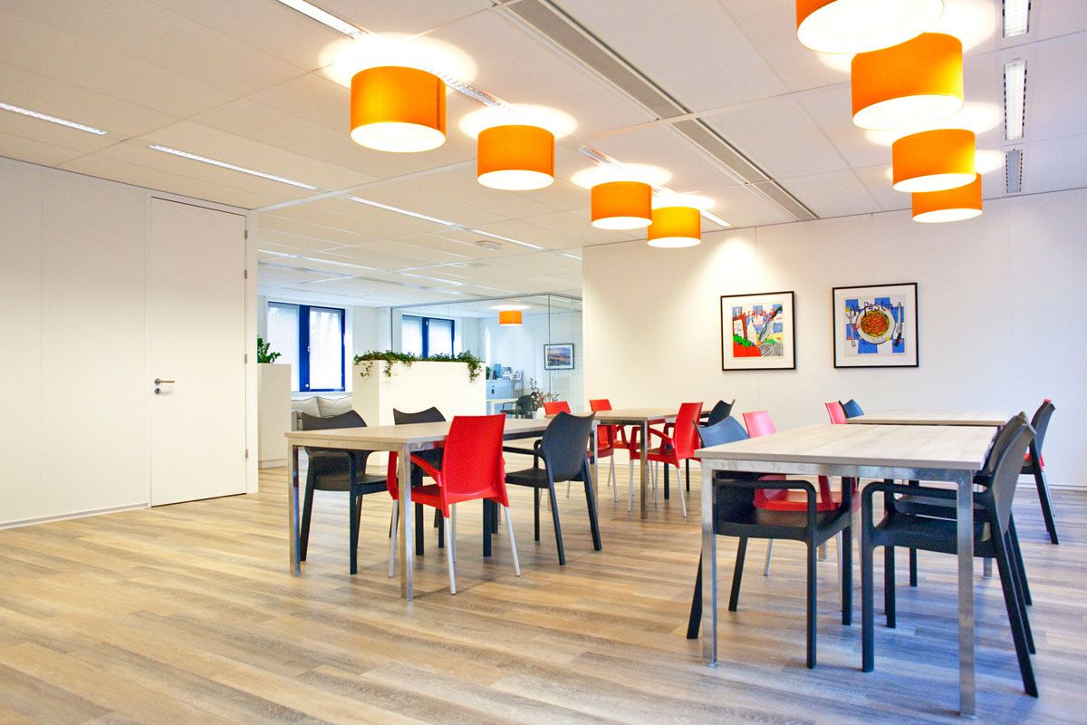 Moderne kantoorinrichting in Zeist met kleurrijke stoelen en oranje hanglampen in de lunchruimte.